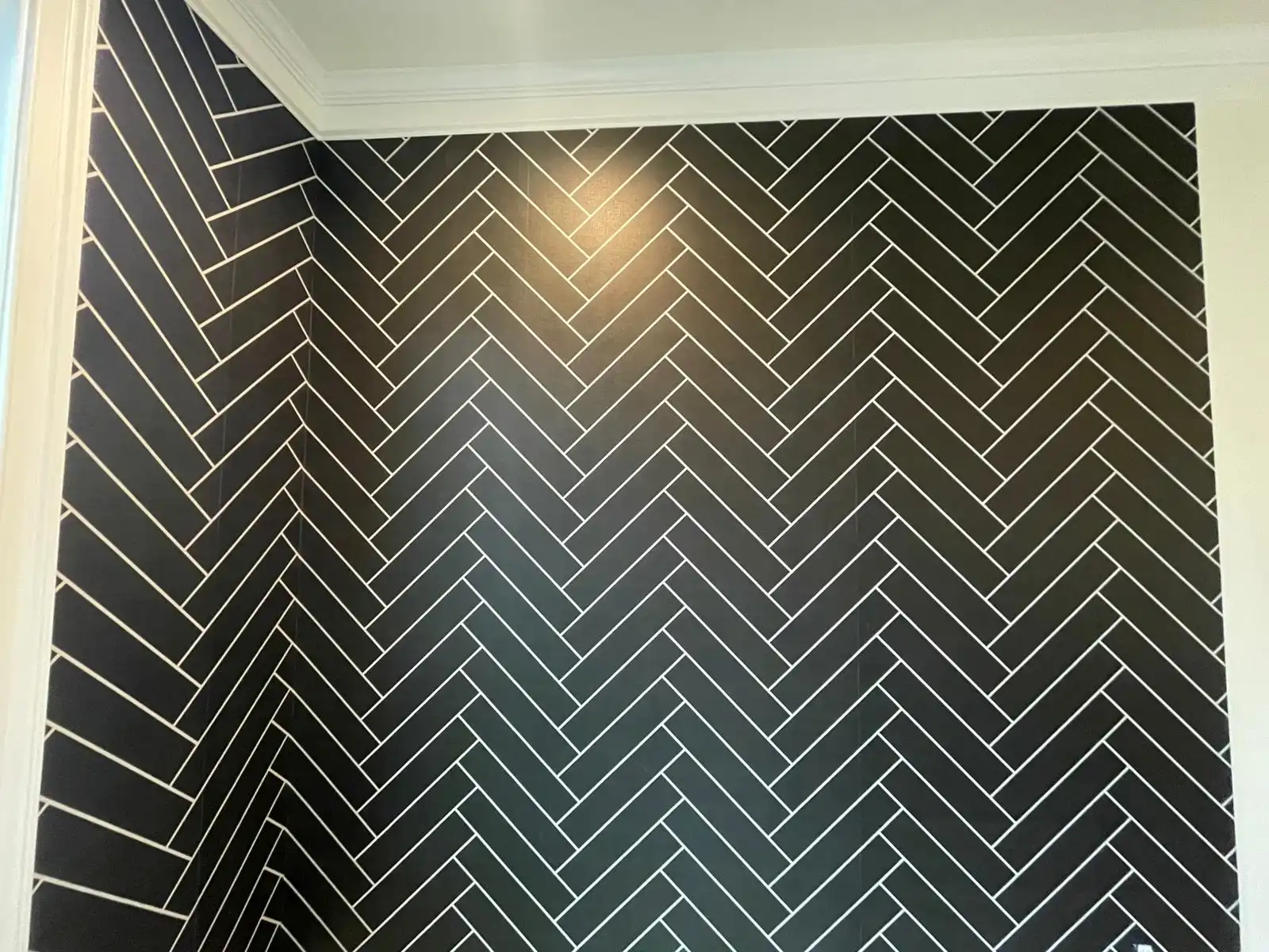 Black herringbone wallcovering framed by white molding.