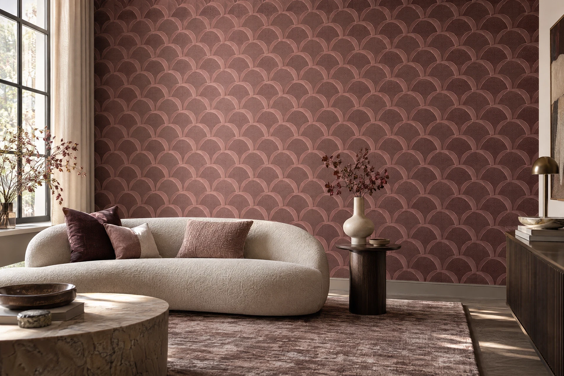 Dusty rose geometric wallpaper behind a cream curved sofa in a sunlit sitting room.